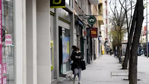 Una mujer con mascarilla espera su turno frente a una sucursal de Bankia