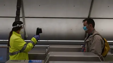 Una voluntaria de la DYA toma la temperatura con una pistola a un viajero en la estaci&oacute;n de metro de Otxarkoaga. En Bilbao (Vizcaya, Pa&iacute;s Vasco, Espa&ntilde;a), a 11 de mayo de 2020.