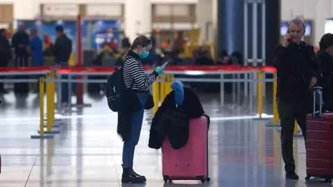 Una turista con mascarilla y guantes en el aeropuerto de M&aacute;laga