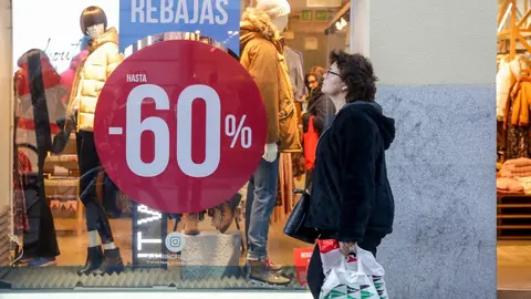 Una mujer pasea junto a una tienda de moda de Madrid, en la que se ofertan las segundas rebajas con ofertas de hasta el 60%.