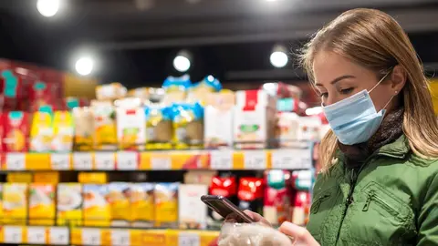 Imagen de una mujer con mascarilla en un supermercado.