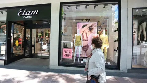Una mujer pasa junto a una tienda Etam en la que se anuncian rebajas de hasta  el 50% el d&iacute;a en el que el Gobierno permite finalmente las rebajas desde hoy en toda Espa&ntilde;a siempre que no generen aglomeraciones, en Madrid (Espa&ntilde;a) a 18 de mayo de 2020.