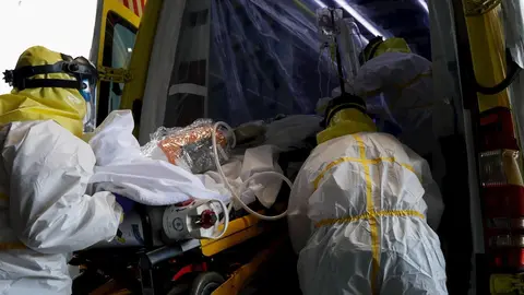 Sanitarios del SUMMA protegidos con un traje protector frente al Covid-19 trasladan a un paciente desde la UVI 