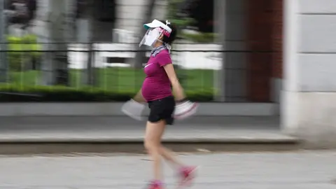 Una mujer embarazada y con visera de protecci&oacute;n pasea cartel durante el tercer d&iacute;a de la desescalada del Gobierno en la fase 0 y el inicio de la semana octava del estado de alarma decretada por el coronavirus. En Madrid (Espa&ntilde;a), a 4 de mayo de 2020.