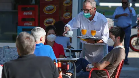Un camarero sirve a los clientes en una terraza de un bar 