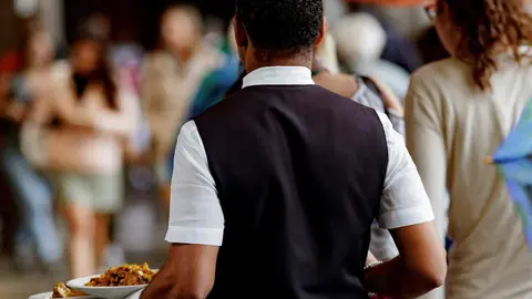 Un camarero porta los platos de los clientes en Madrid.