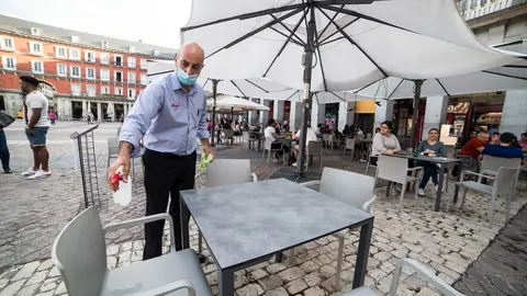 Un camarero desinfecta una mesa
