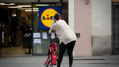 Una mujer espera con su carro de la compra a poder entrar a un supermercado Lidl tras las medidas de aforo impuestas por seguridad, durante el segundo d&iacute;a laborable del estado de alarma por el coronavirus, en Barcelona (Espa&ntilde;a), a 17 de marzo de 2020.