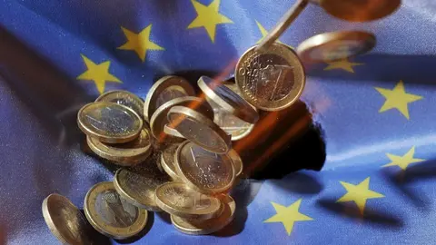 Monedas de euro sobre la bandera de la UE