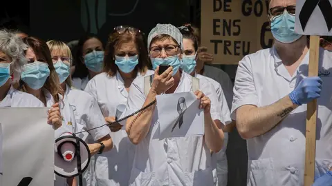 Una sanitaria habla por un meg&aacute;fono junto a otros compa&ntilde;eros de profesi&oacute;n a las puertas del Hospital Cl&iacute;nic de Barcelona donde sostienen pancartas y crespones negros para reivindicar contratos dignos y m&aacute;s personal. En Barcelona, a 27 de mayo de 2020.