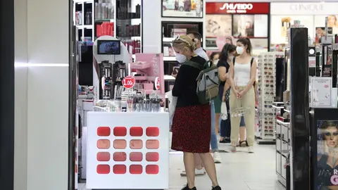Varias personas con mascarilla en una perfumer&iacute;a abierta en el primer d&iacute;a de la fase 1 en Madrid.