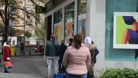 Personas en fila guardan su turno para entrar en una oficina de Bankia.