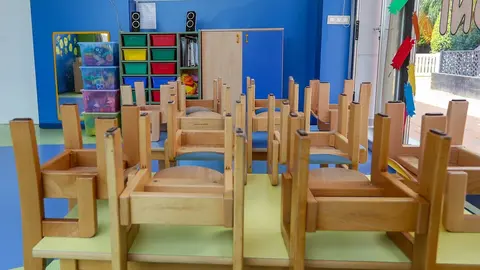 Mesas y sillas recogidas en un aula de un colegio.