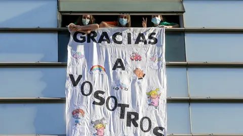 Tres sanitarias del Hospital General Universitario Gregorio Mara&ntilde;&oacute;n en una ventana del hospital.