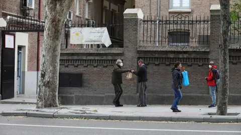 Varias personas esperan en cola para entrar en el comedor de las Hijas de la Caridad de San Vicente de Pa&uacute;l en el madrile&ntilde;o barrio de Chamber&iacute;, donde se reparten alimentos a los m&aacute;s necesitados, en Madrid (Espa&ntilde;a) a 28 de abril de 2020.