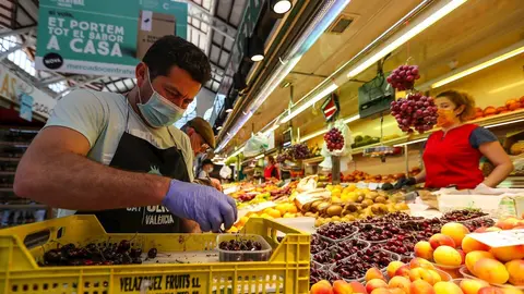 Un hombre trabaja colocando la fruta en una una fruter&iacute;a del Mercado Central de Valencia.