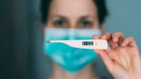 Imagen de recurso de una mujer con un term&oacute;metro y mascarilla.