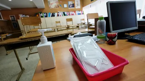 Mascarillas y gel desinfectante en la mesa del profesor de un aula. Archivo
