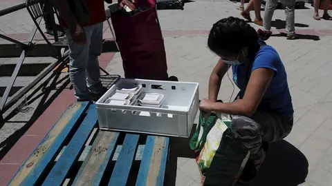 Una mujer recoge productos a las puertas de la Parroquia Santa Mar&iacute;a Micaela donde han acudido para recibir una ayuda alimentaria d