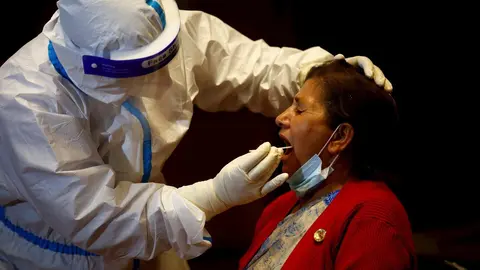 07 May 2020, Nepal, Kathmandu: A health worker takes a throat swab sample for the coronavirus PCR test from a woman, as the government is testing the members of National Assembly and House of Representatives for the novel coronavirus a day before the new 