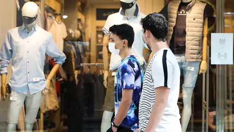 Dos j&oacute;venes pasan junto a una tienda de ropa del Centro Plaza Norte 2, La C&uacute;pula de Madrid, durante el segundo d&iacute;a de la Fase 2 de desescalada, y un d&iacute;a despu&eacute;s de reanudar su actividad puesto que se permite la reapertura de centros comerciales mayores de