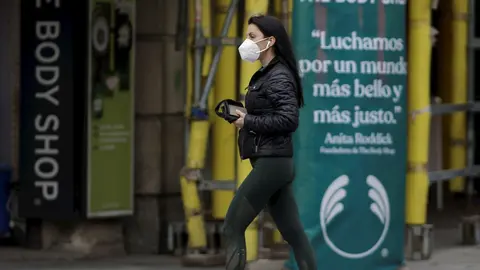 Una mujer camina con una mascarilla por la capital donde desde este pasado lunes las 2.882 farmacias madrile&ntilde;as han entregado de forma gratuita siete millones de mascarillas FFP2 modelo KN95 entre la poblaci&oacute;n de la Comunidad de Madrid  