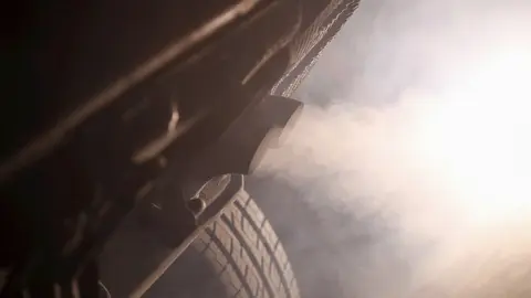 Tubo de escape de un coche emitiendo poluci&oacute;n.
