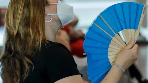 Una mujer con mascarilla se abanica en Madrid (Espa&ntilde;a), a 29 de junio de 2020. El calor pone desde este lunes en aviso a una quincena de provincias de Andaluc&iacute;a, Castilla y Le&oacute;n, Castilla-La Mancha, Extremadura y Madrid, por temperaturas m&aacute;ximas que van d