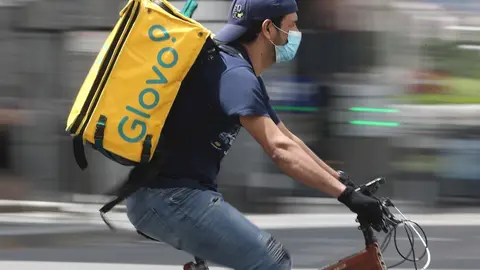Un repartidor de Glovo monta una bicicleta durante su jornada laboral.