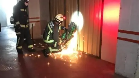 Bomberos abren la puerta del garaje donde se ha encontrado al hombre fallecido