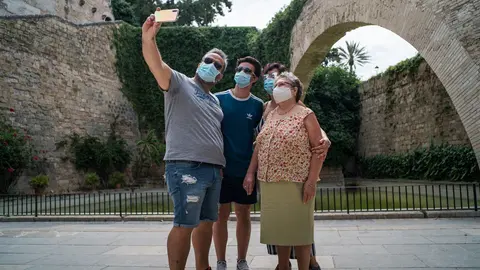 Varios turistas se hacen una foto junto a los Jardines de S'Hort del Rei de Palma de Mallorca durante el primer d&iacute;a de uso obligatorio de la mascarilla en Baleares por el Covid-19, en Palma de Mallorca, Islas Baleares (Espa&ntilde;a) a 13 de julio de 2020. 