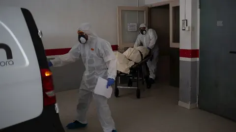 Varios operarios protegidos de los Servicios Funerarios Memora trasladan un cuerpo de una residencia  en el garaje de una residencia de ancianos 