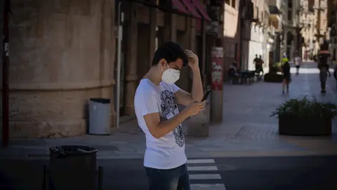 Un joven protegido con mascarilla camina por una calle del centro de Lleida, capital de la comarca del Segri&agrave;, en Lleida.