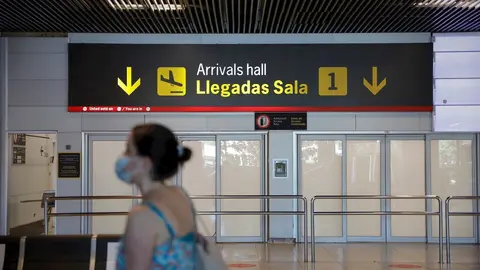 Una persona con mascarilla pasa junto a la entrada de la sala de llegadas 1 de la Terminal 1 del Aeropuerto de Barajas, en Madrid (Espa&ntilde;a) a 4 de julio de 2020.