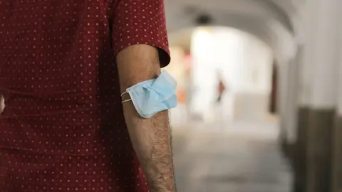 Un hombre lleva la mascarilla en el brazo en M&eacute;rida