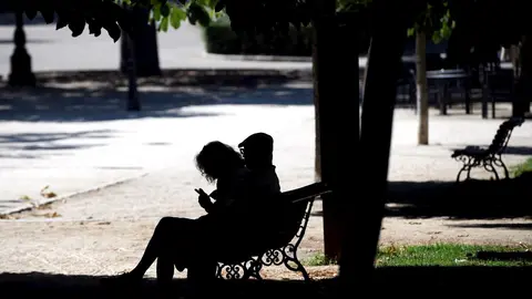 Pareja sentada en un banco a la sombra