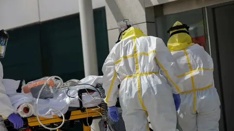 Varios sanitarios trasladan a un paciente desde el interior de la unidad m&oacute;vil del SUMMA hasta la entrada del Hospital Puerta de Hierro tras haberle trasladado anteriormente desde la UVI del hospital temporal de IFEMA, durante un d&iacute;a de trabajo del Servic
