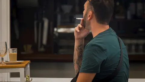 Una persona fuma en una terraza durante el primer d&iacute;a de la prohibici&oacute;n de realizarlo en la v&iacute;a p&uacute;blica en Andaluc&iacute;a. En Sevilla, (Andaluc&iacute;a, Espa&ntilde;a), a 17 de agosto de 2020.