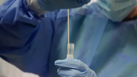 Una trabajadora sanitaria sostiene una probeta con una prueba PCR. Archivo