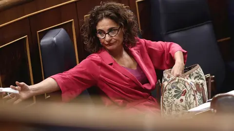 La ministra de Hacienda, Mar&iacute;a Jes&uacute;s Montero, busca en su bolso una mascarilla y un diputado le presta otra  en el Congreso durante la sesi&oacute;n plenaria.