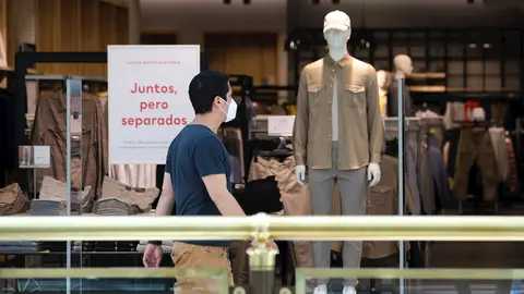 Un hombre pasa junto a una tienda de ropa del Centro Plaza Norte 2, La C&uacute;pula de Madrid