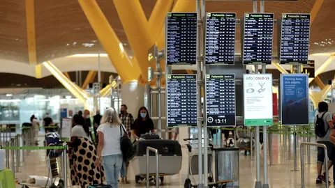 Pasajeros junto a p&aacute;neles de informaci&oacute;n en la Terminal T4 del aeropuerto Adolfo Su&aacute;rez Madrid-Barajas, en Madrid (Espa&ntilde;a).