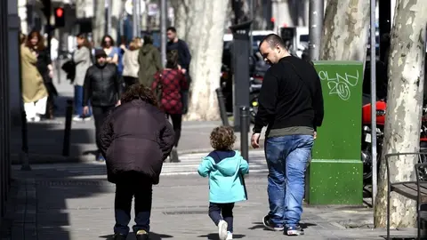 Unos padres pasean junto a su hija por la calle