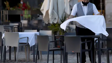 Un camarero prepara la mesa de una terraza de un establecimiento
