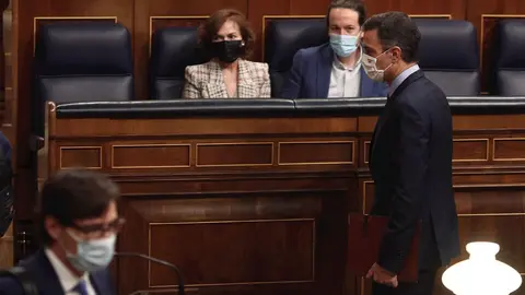 El presidente del Gobierno, Pedro S&aacute;nchez, pasa por delante de vicepresidenta primera del Gobierno, Carmen Calvo, y vicepresidente segundo del Gobierno, Pablo Iglesias, durante una sesi&oacute;n de control al Gobierno en el Congreso, en Madri, a 28 de octubre