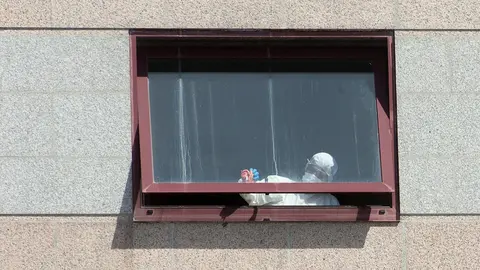 Un trabajador protegido es visto por uno de los cristales de la  residencia de mayores DomusVi de Outeiro de Rei en Lugo, Galicia (Espa&ntilde;a), a 8 de septiembre de 2020. 