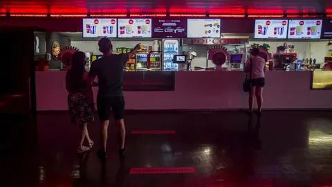 Dos personas eligen un men&uacute; de palomitas y refresco en el primer fin de semana con estrenos en las salas de cine, el pasado mes de junio