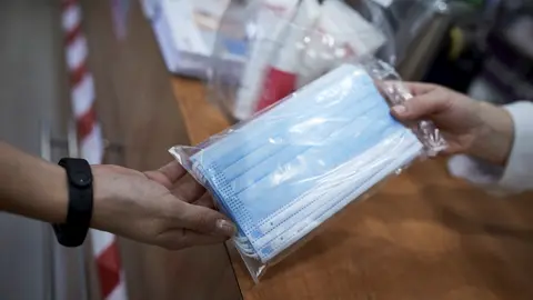 Una farmac&eacute;utica ense&ntilde;a un paquete de mascarillas