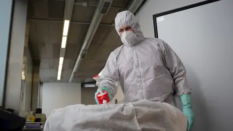 Un operario del Crematorio de Girona desinfecta el cuerpo de una persona fallecida con Covid-19 y su ata&uacute;d, antes de introducirle en el horno crematorio