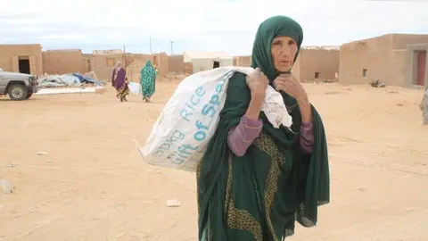 Una refugiada saharaui carga un saco con comida del Programa Mundial de Alimentos